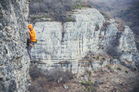 Athletic man climbs very high limestone rock with rope, lead climbing. Sport climbing outdoor.の写真素材