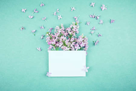 Flower card made of lilac bouquet  and white paper envelope  in the center. For holiday project.の写真素材