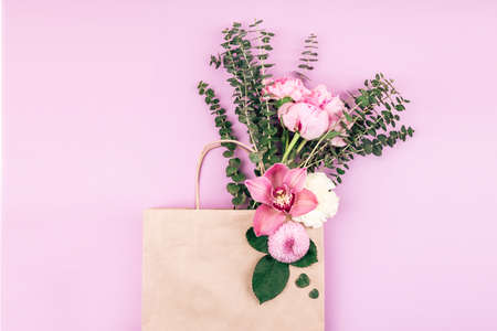 Flower card made of roses, orchid, chrisantemum, carnation and baby eucalyptus leaves on craft paper bag. For holiday project.の写真素材