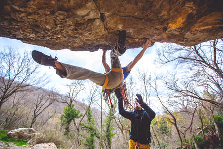 Athletic man climbs an overhanging rock with rope, lead climbing. Sport climbing outdoor.の写真素材