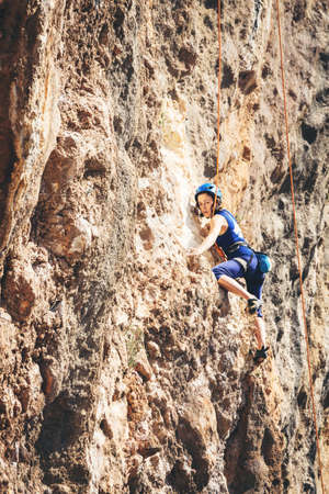 Young athletic woman climbs an overhanging rock with rope in Turkey. Sport climbing, lead. Side view.の写真素材