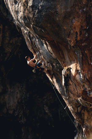 Athletic man climbs an overhanging rock with rope, lead climbing in Turkey. Sport climbing outdoor.の写真素材