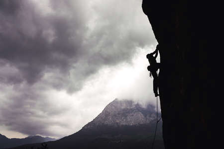Silhouette of athletic man climbs an overhanging rock with rope, lead climbing in Turkey. Sport climbing outdoor.の写真素材