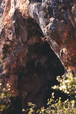 Athletic man climbs an overhanging rock with rope, lead climbing in Turkey. Sport climbing outdoor.の写真素材