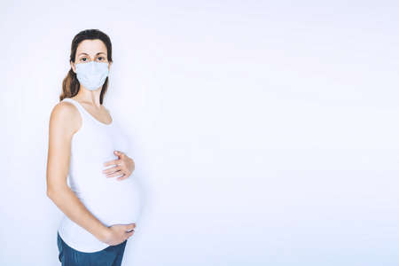 Young pregnant woman in protective medical mask covered her face. Virus protection and hygiene.の写真素材