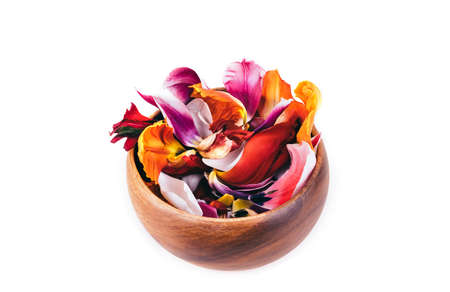 Abstract colorful tulip petals flowers in a wooden bowl on white isolated background. Macro frame. Summer flower card.の写真素材