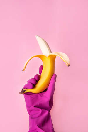 Hand in pink protective glove hold a banana.の写真素材