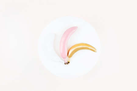 White, pink and golden colored bananas on white circle background. Flat lay style, tropic summer visual.の写真素材