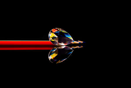 Rainbow bright colored  pencils and drop shaped crystal on isolated black . Art education concept.の写真素材