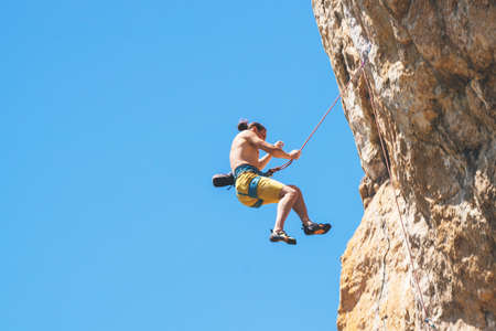 Athletic man climbs an overhanging rock with rope, lead climbing. Sport climbing outdoor.の写真素材