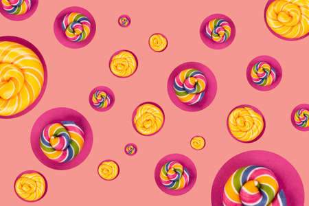 Many colorful lollipop candys arranged in lines on pink background. Flat lay concept.の写真素材