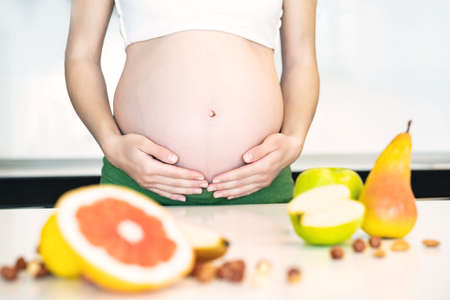 Cropped frame of pregnant woman cooking fruit granola breakfast. Healthy food concept for pregnant woman.の写真素材