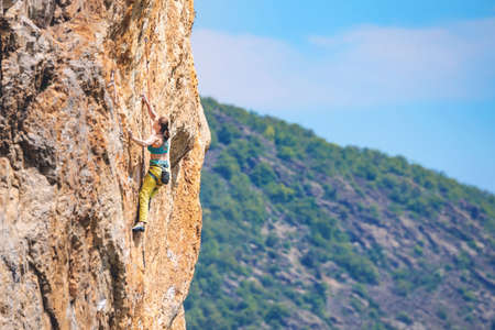 Athletic beautiful woman climbs an overhanging rock with rope, lead climbing. Sport climbing outdoor.の写真素材