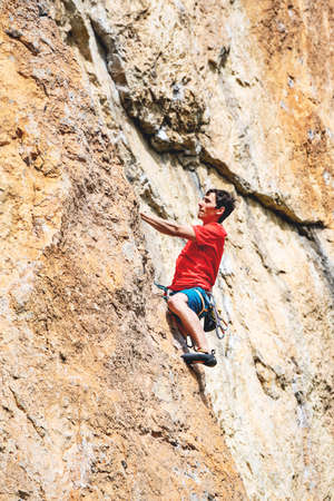 Athletic man climbs an overhanging rock with rope, lead climbing. Sport climbing outdoor.の写真素材