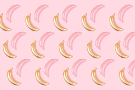 Modern pattern pop flat lay style made of golden and pink colored bananas on pink background. Festive or summer concept.の写真素材
