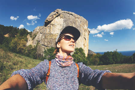 Smiling young woman taking selfie outdoor, travel selfie. Sea and mountains view.の写真素材