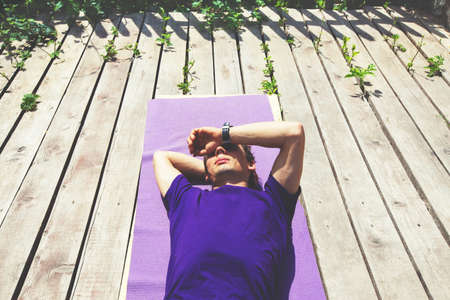 Man relaxing in the sun on a a deck, rural scenic weekend.
