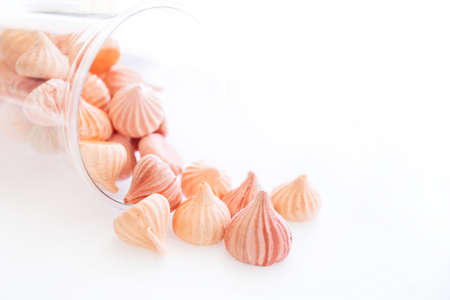 Soft pink color of mini marshmallows dessert spilling out of a glass on isolated whiteの写真素材