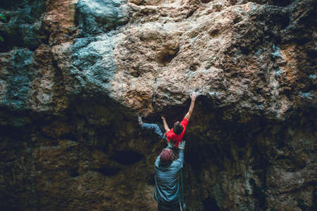 Athletic man climbs an overhanging rock with rope, lead climbing. Sport climbing outdoor.の写真素材