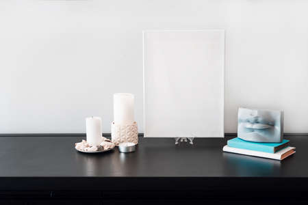 Interior design of room, blank white canvas for artist's mock-up, lips shaped vase with dry flowers bouquet, candles, white books on black table and white wall. Minimalism style.の写真素材