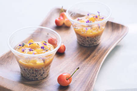 Two cups of granola breakfast served with lavender flowers, fruit jam and cherry on a wooden tray. Concept of heakthy food.の写真素材