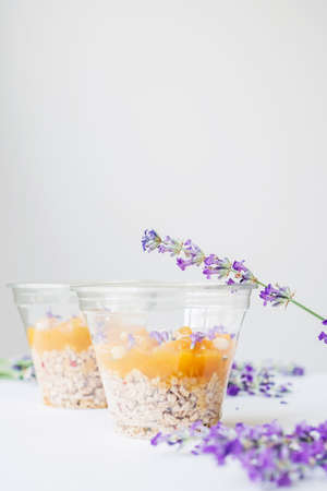 Two cups of granola breakfast served with lavender flowers, fruit jam and cedar nuts on  a wooden tray. Concept of healthy food.の写真素材