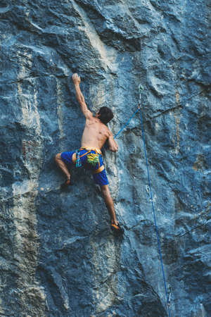 Athletic man climbs an overhanging rock with rope, lead climbing. Sport climbing outdoor.の写真素材