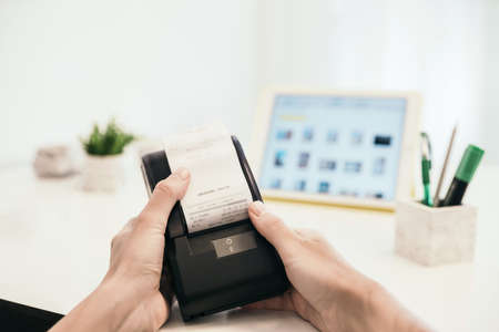 Hand holding online  sales register machine with invoice, consept of small online business staying...