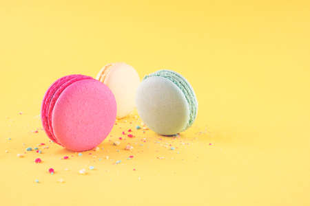 Three colorful macarons dessert llying among its crumbs, concept for holiday party.の写真素材