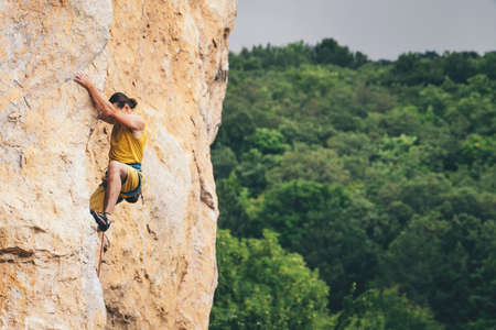 Athletic man climbs an overhanging rock with rope, lead climbing. Sport climbing outdoor.の写真素材