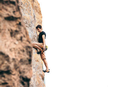 Athletic man climbs an overhanging rock with rope on isolated white, lead climbing. Sport climbing outdoor.の写真素材