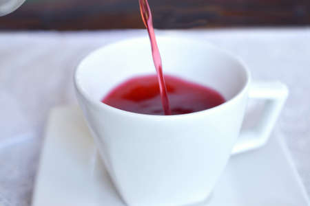 Pouring hibiscus tea in white cup