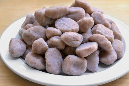 Closeup on a plate with whole wheat gnocchi on white plate, over wooden table, from the sideの写真素材
