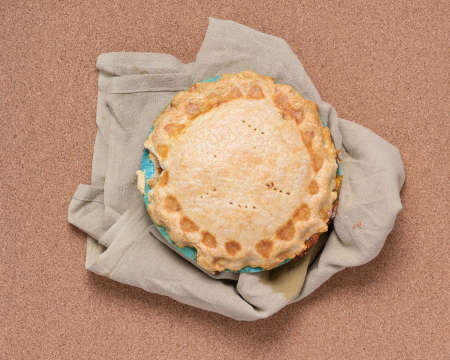 A generic pie on wooden table, on tan flower sac cloth, over cork backgroundの写真素材