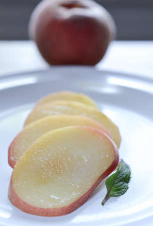 Sliced white peach on plate, with white peach on the backgroundの写真素材