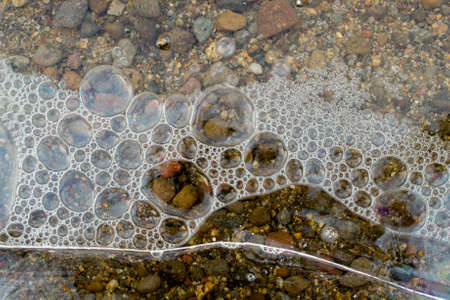 Air bubbles underneath frozen layer of water at the margin of a lake, in the winter- abstract...