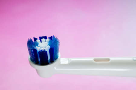 Close-up on the side of the head of a new, white and blue head of an electric toothbrush against...