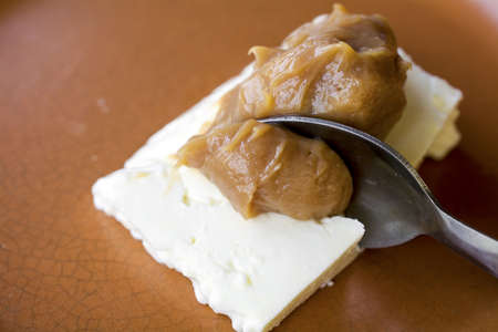 Closeup on spoon picking a serving of caramel cream (doce de leite) with white cheese (Queijo de...