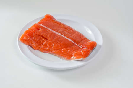 Raw wild king Salmon Fillet lying on white place, against white backgroundの写真素材