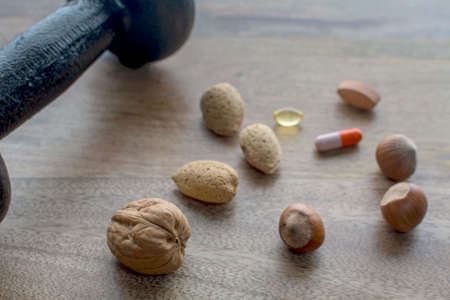 Closeup on dumbbell, nuts and dietary supplements on wooden table : fitness and weight loss concept on a vegan diet.の写真素材