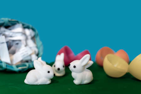 Easter basket filled with plastic eggs rolls over and little white bunnies hatch from cracked colorful plastic eggsの写真素材