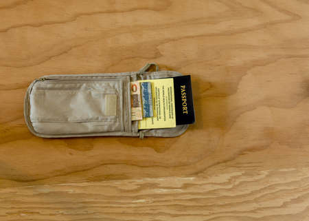 Travelig to Brazil: essential for a trip laid on a wooden table:  a passports and International Certificate of Vaccination, and Brazilian currency, in a neck passport walletの写真素材