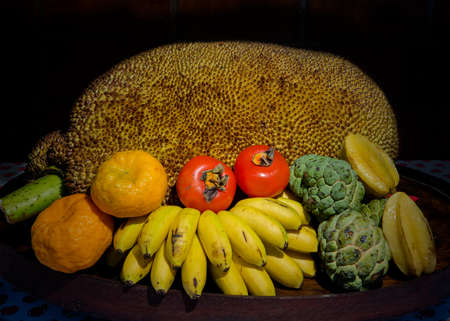 Closeup on Tripical fruits in wooden basket, against black background - tropical still lifeの写真素材