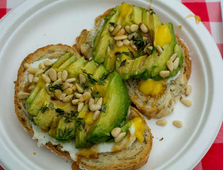 Gourmet Mexican avocado toast garnished with cream cheese, lemon zest, pine nuts, and rosemary, on...