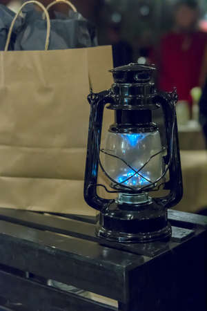Black, old, 1800s Kerosene lamp decoratign a store, close-up, next to a paper bag with wrapped presents in it, side viewの写真素材