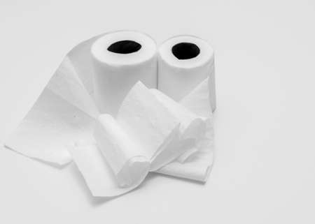 Two rolls of white toilet paper on white background, partly unrolled, viewed from an angleの写真素材