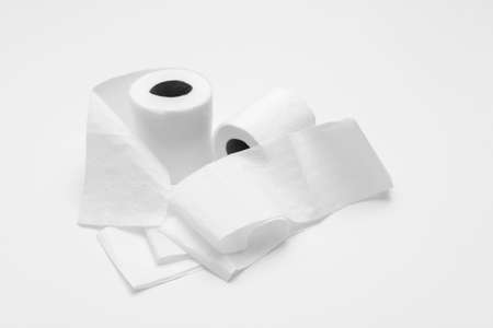 Two rolls of white toilet paper on white background, partly unrolled, viewed from an angleの写真素材