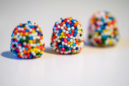 Three multi-colored  liquorice candies on white background, lined up, selective focus on middle one,...