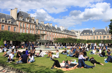 PARIS, FRANCE - MAY 24, 2015: People relaxing on green lawns of the famous Place des Vosges - the oldest planned square in Paris located in Marais district on May 24, 2015 in Parisのeditorial素材