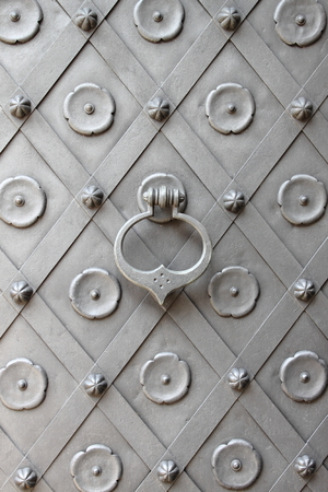 Bronze knocker on a metal doorの写真素材